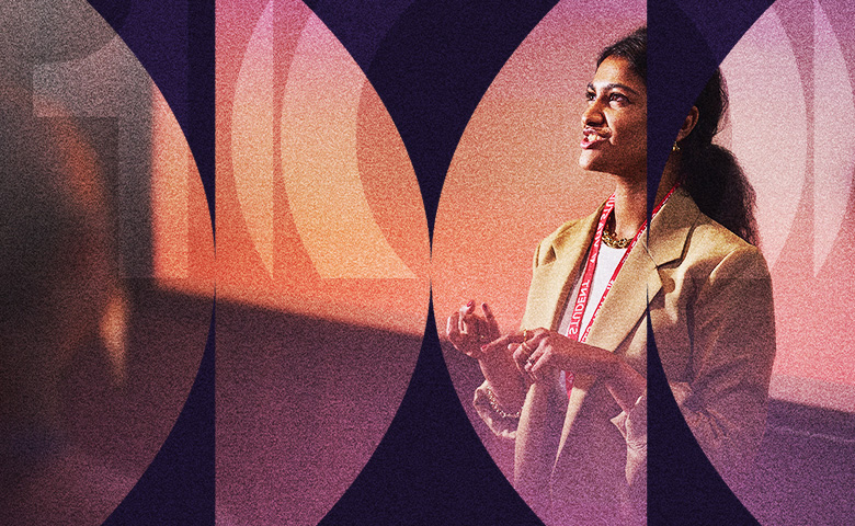 A person stands and speaks, projected with a purple gradient overlay that symbolizes their journey beyond ambition. They wear a tan blazer and lanyard, gesturing passionately. The softly blurred background hints at an inspiring presentation or speech setting.