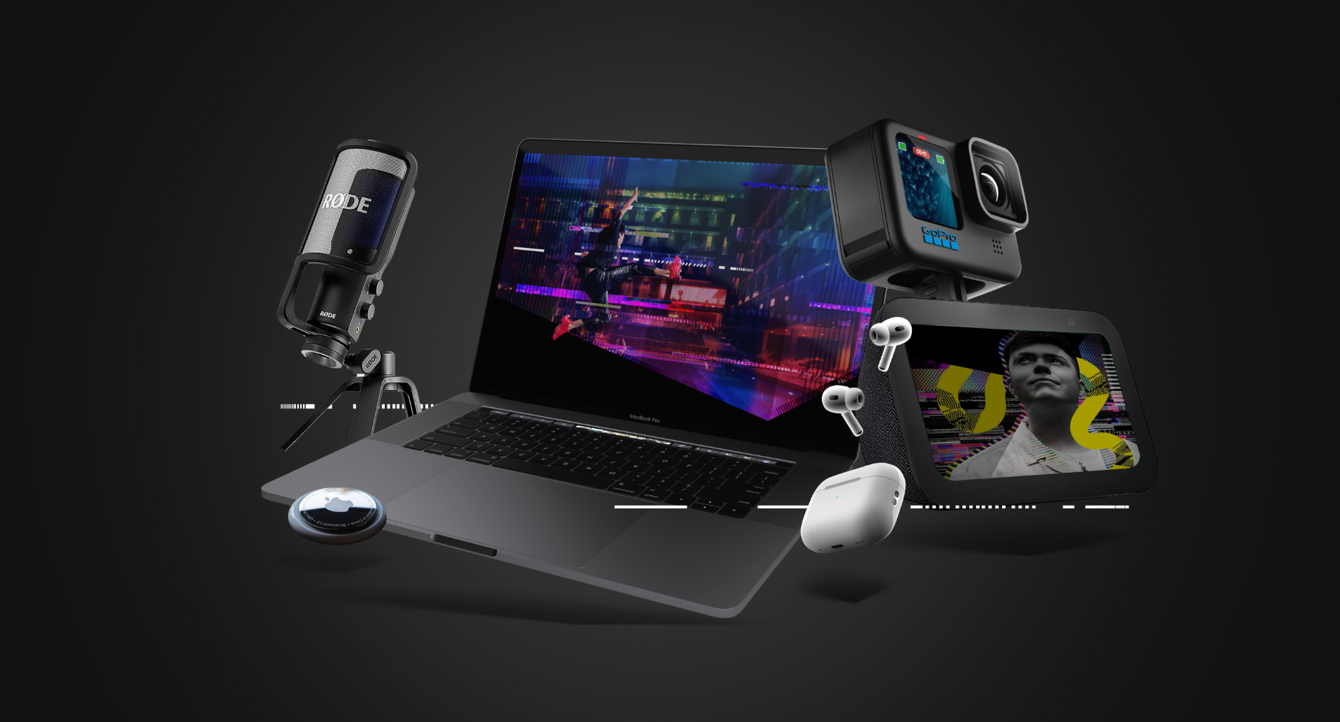 A laptop displaying a colorful cityscape is surrounded by gadgets venturing beyond ambition: a microphone, action camera, smart display showing a person, stylus, and earbuds. All items are set against a dark background.