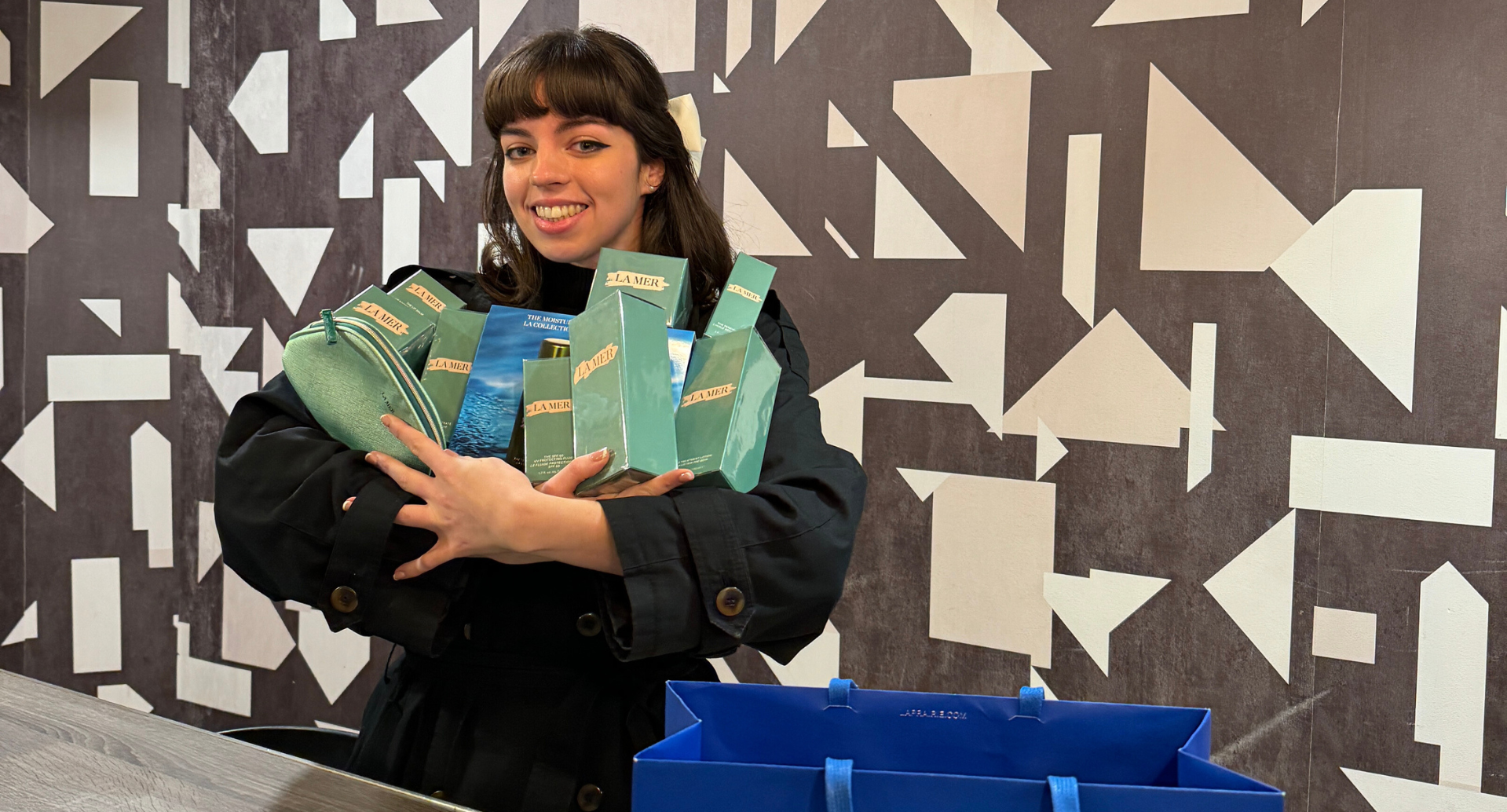 Girl smiling holding a La Mer Beauty product bundle