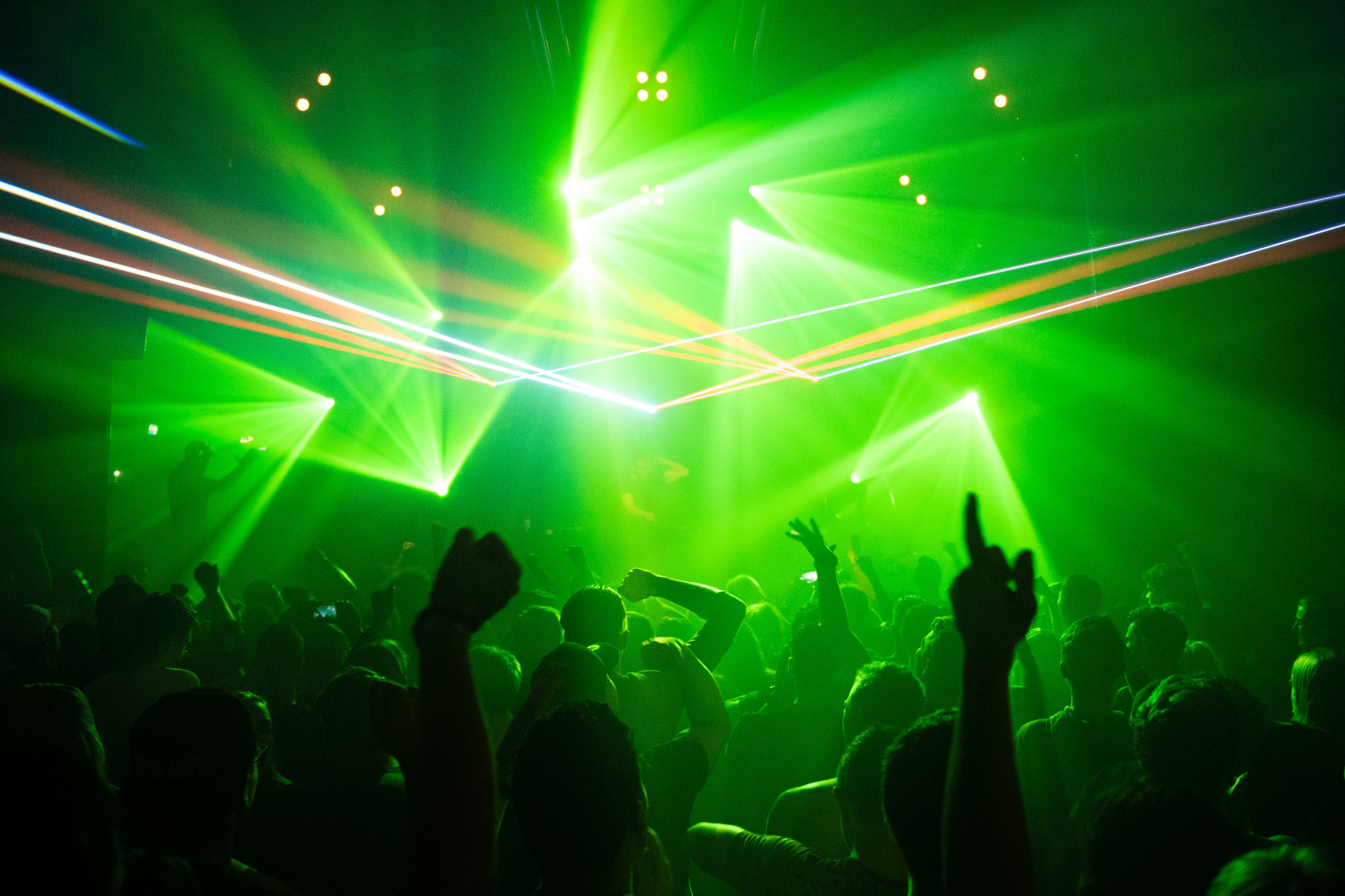 A lively concert scene in Barcelona with a crowd of people silhouetted against a backdrop of vibrant green lasers and stage lights. With hands raised, the atmosphere rivals the city's renowned clubs, creating an energetic and dynamic vibe akin to unforgettable parties.