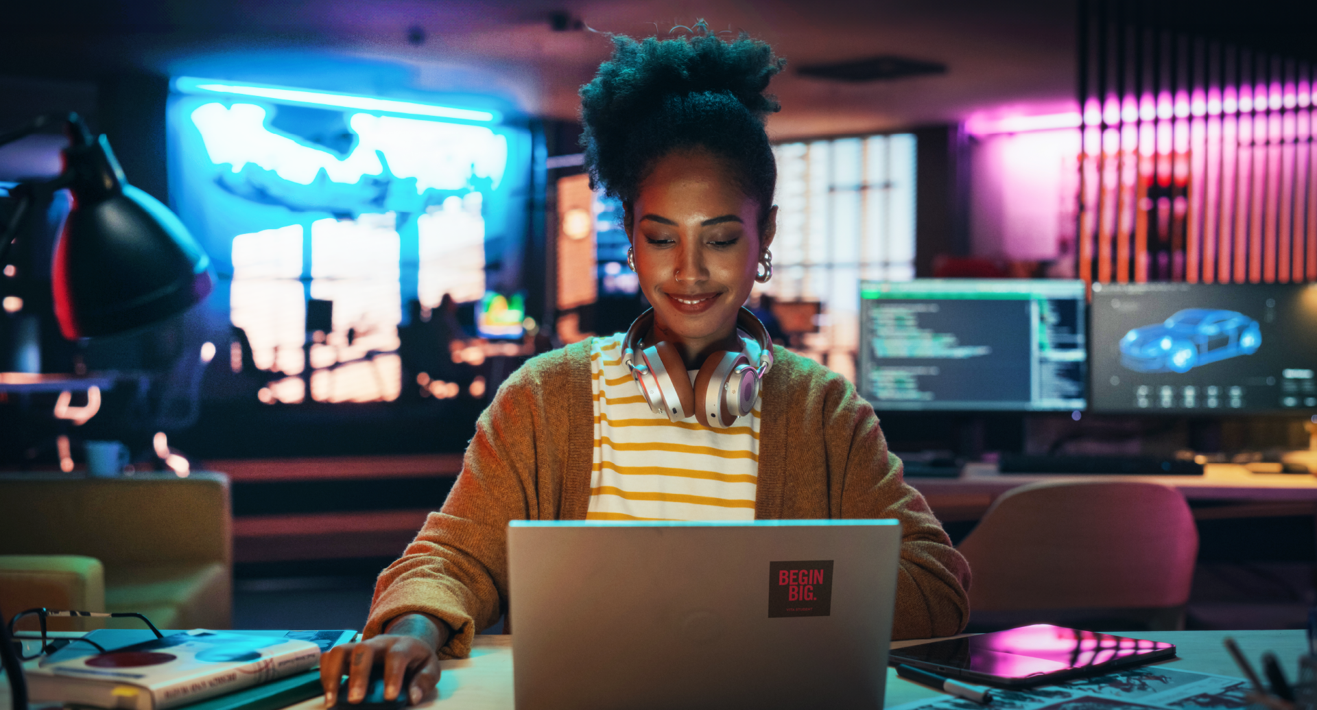 A person wearing headphones and a brown sweater works on a laptop in a dimly lit room with neon lights, immersed in tech-focused conditions. The background shows computer screens and a cup on the desk, reflecting an atmosphere ripe for crafting terms or exploring a price match guarantee.