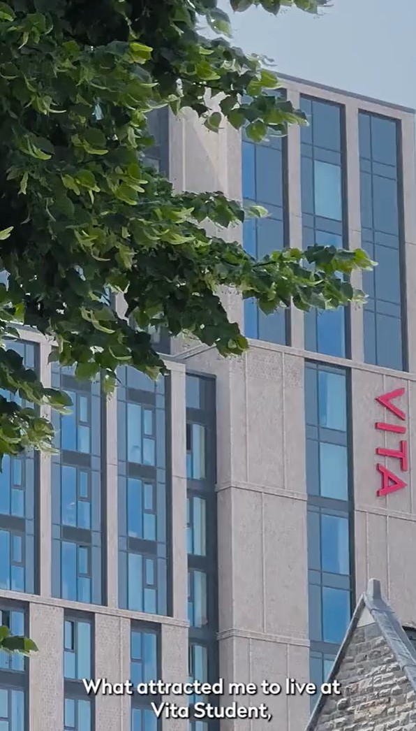 A modern building with multiple windows, the words "VITA" in red on the wall, partly obscured by green tree leaves. At the bottom, it reads, "What attracted international students like me to live at Vita Student.