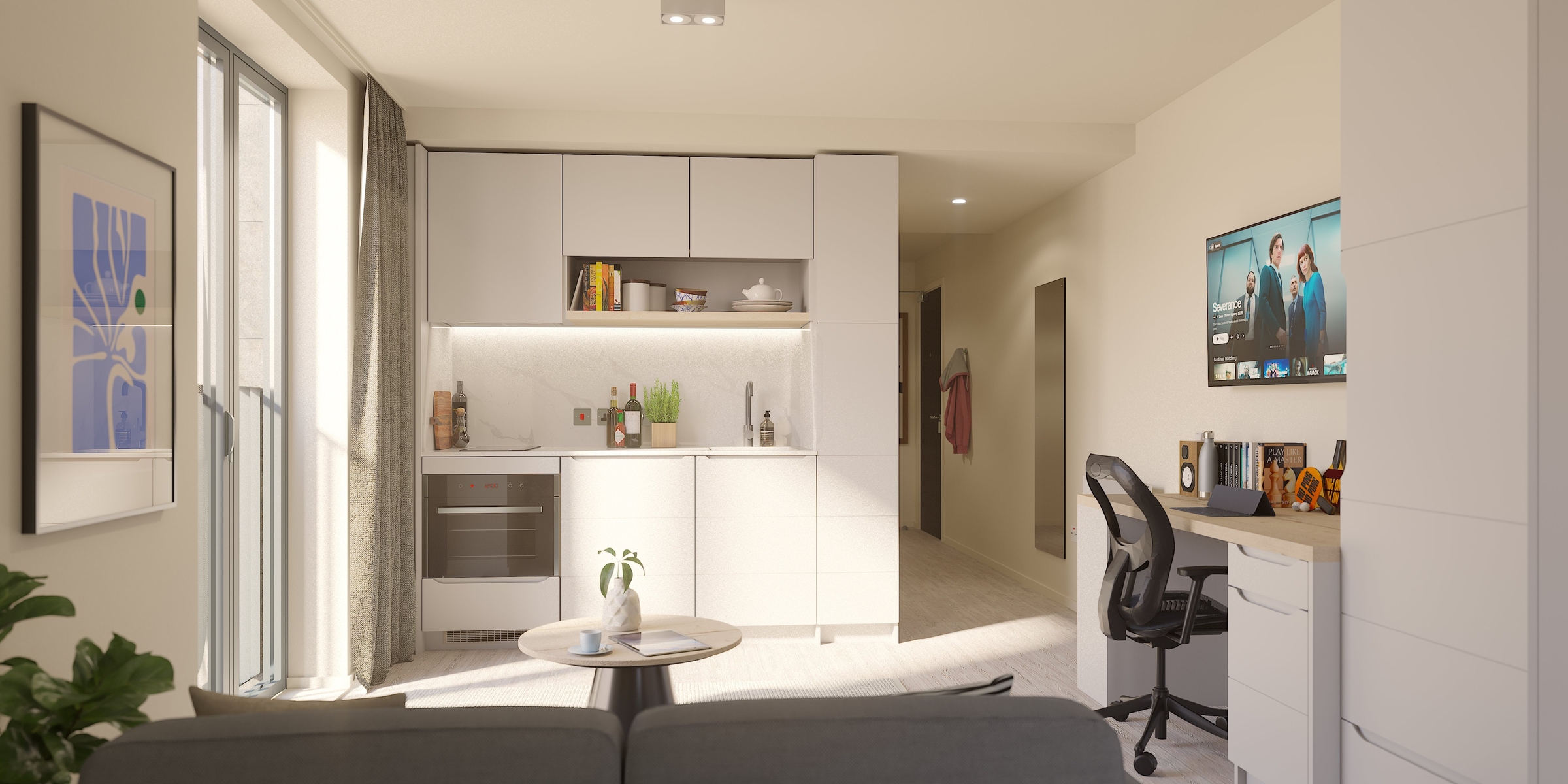 A modern New Waverley studio apartment with a compact kitchen, round coffee table with a plant, desk and office chair, wall art, and TV on the wall. Natural light streams in through large windows with curtains.