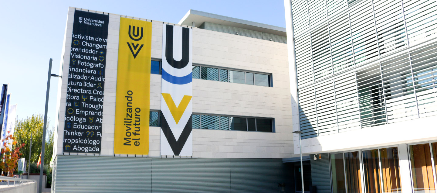 Modern building with large banners on the facade displaying the Universidad Villanueva logo and slogan “Movilizando el futuro.” Ideal for student accommodation in Madrid, it features white paneling and striking vertical windows.