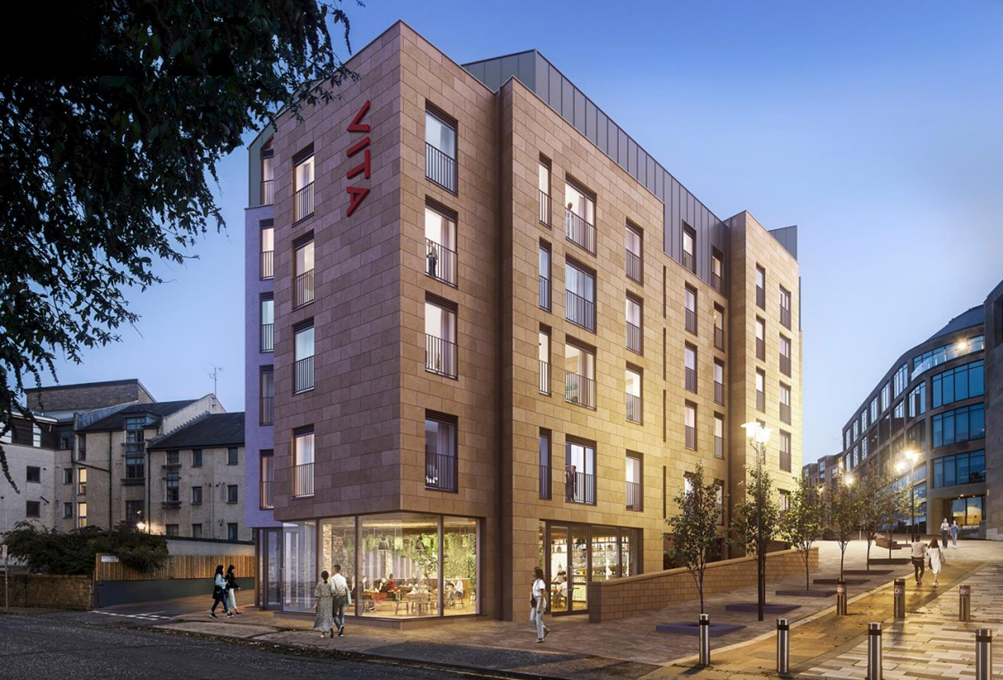A modern six-story building with large windows and warm exterior lighting at dusk; people walk on the sidewalk and a café is visible on the ground floor. The building sign reads “CLAY.”.