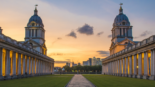 Two grand domed buildings with colonnades face each other at sunset, separated by a grassy lawn and path, with a city skyline in the distance—a classic London student guide scene under a colorful sky.