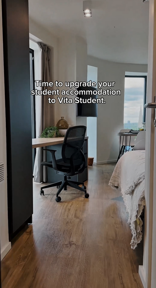 A modern, tidy student bedroom with a desk, chair, computer monitor, bed, and large window. Text over the image reads, "Time to upgrade your student accommodation to Vita Student.