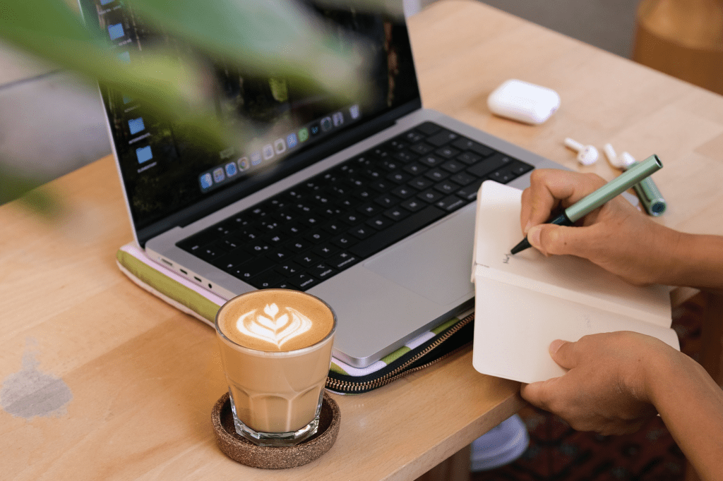 A person working at a cafe with a coffee and laptop.