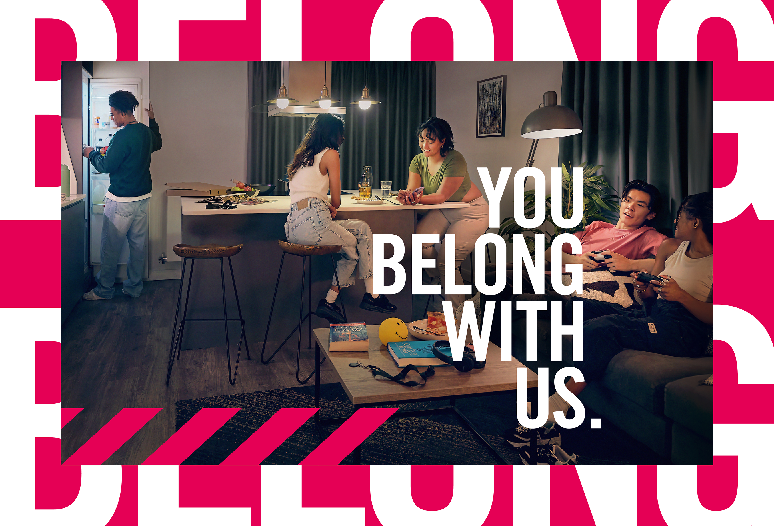 Four young adults relax in a cozy living room, talking, eating, and playing games. Bold white text reads, "You Belong With Us," over a pink and white graphic background.