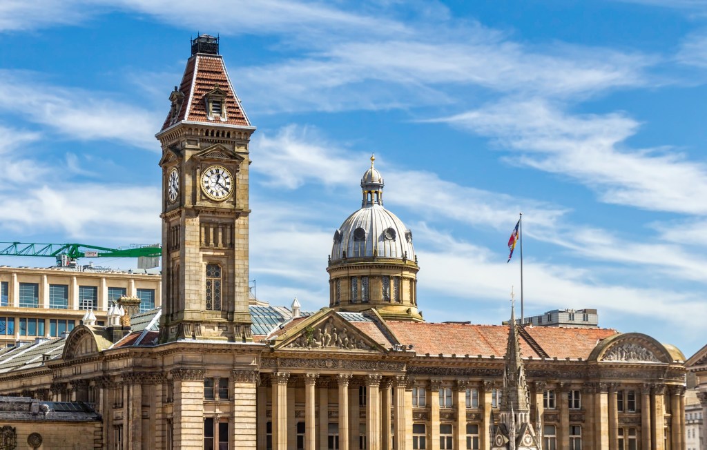 Historic building with a clock tower and domed roof under a blue sky with wispy clouds; columns line the facade, and a flag is visible on a pole to the right—popular with students exploring Gough Street and searching for things to do nearby.