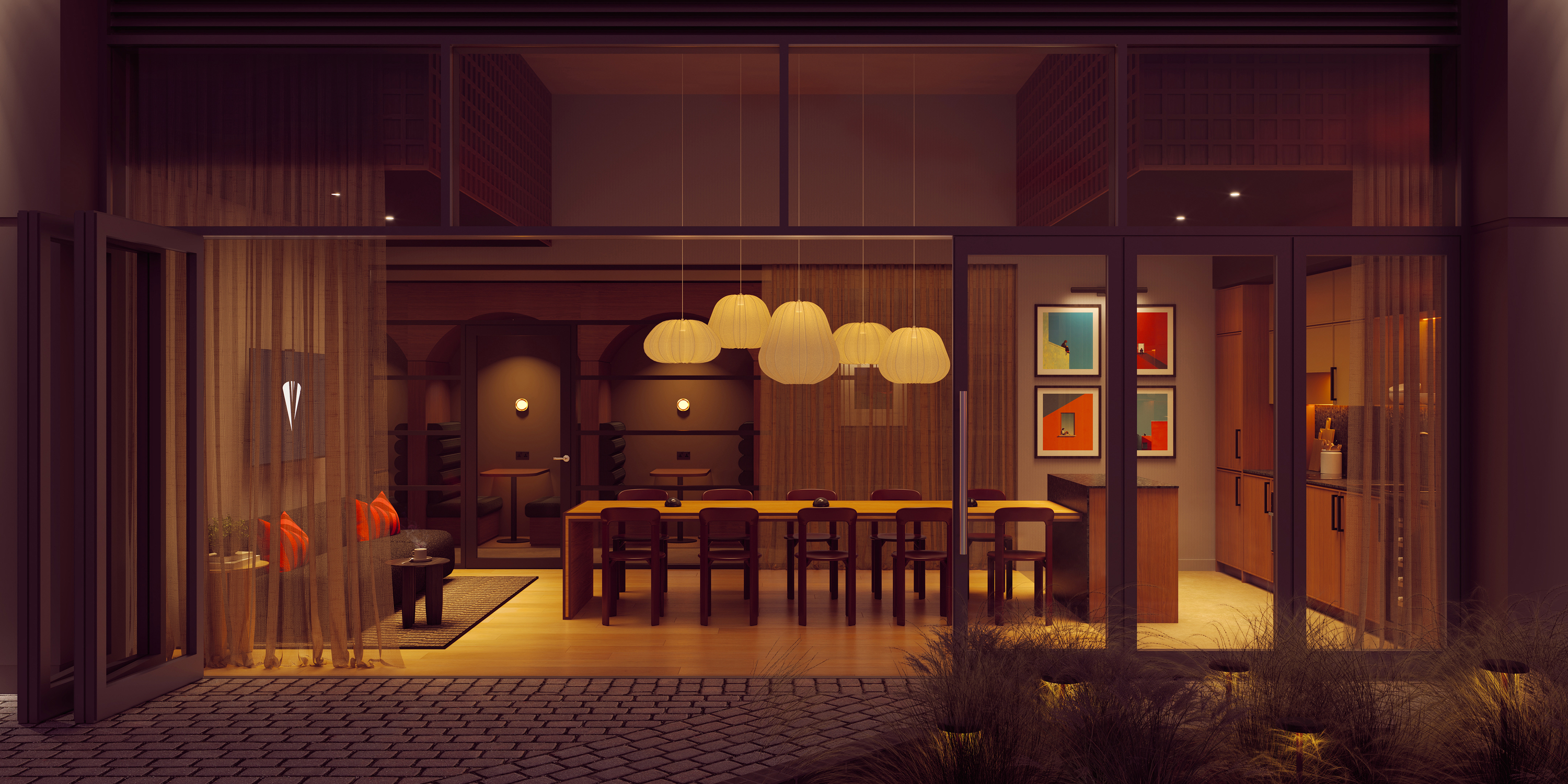 A cozy, modern dining room on India Street is seen through glass doors, featuring a long table with pendant lights, warm wood accents, red pillows, and colorful framed art on the wall.