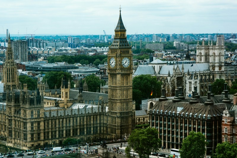 Aerial view of Big Ben and the Houses of Parliament in London, surrounded by historic buildings, trees, and cityscape under a cloudy sky—a vibrant snapshot of the UK capital, renowned for being among the QS Best Student Cities in 2027.