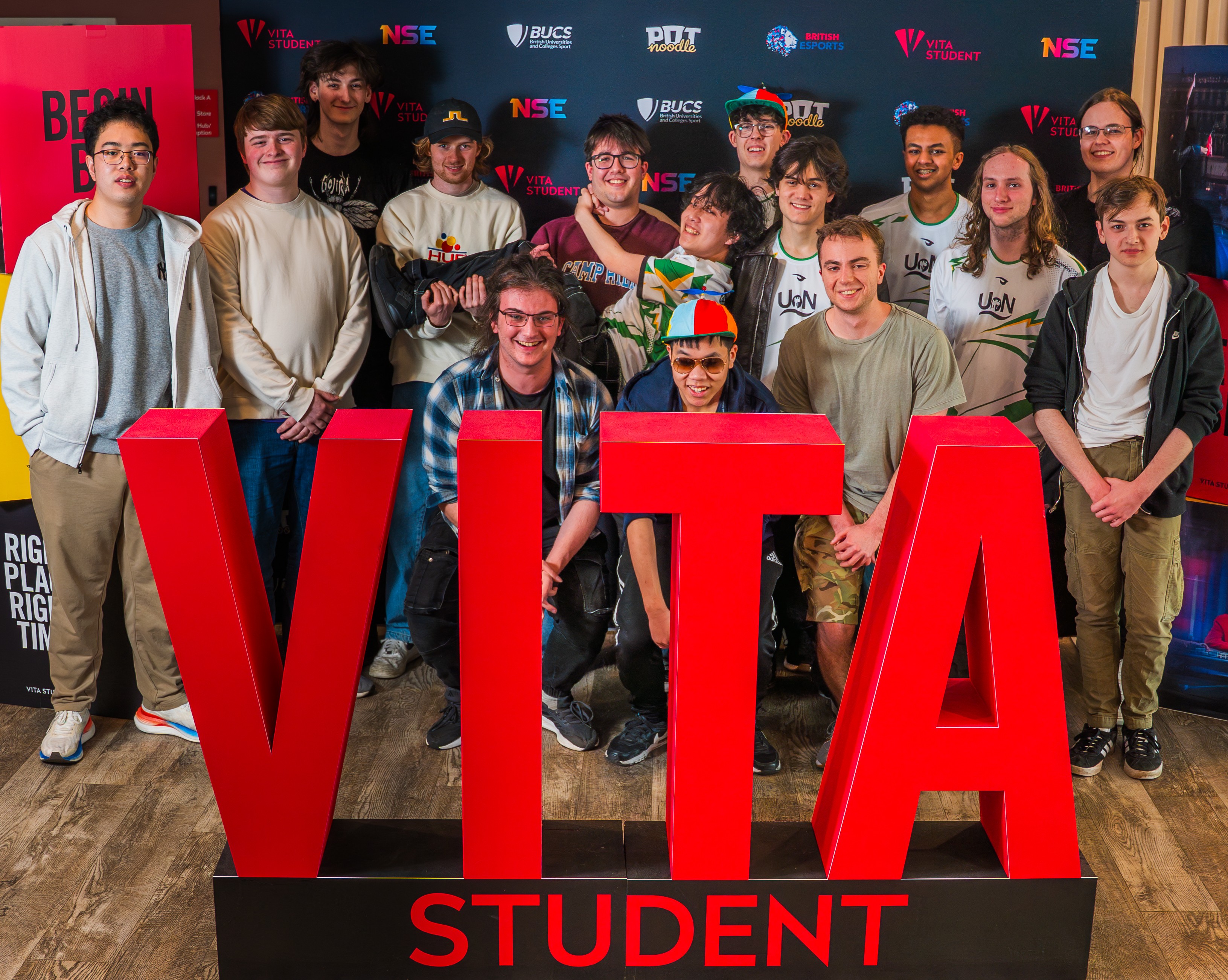 Fifteen university students pose behind large red letters spelling “VITA STUDENT” at an NSE partnership event, with corporate logos visible on the wall behind them.