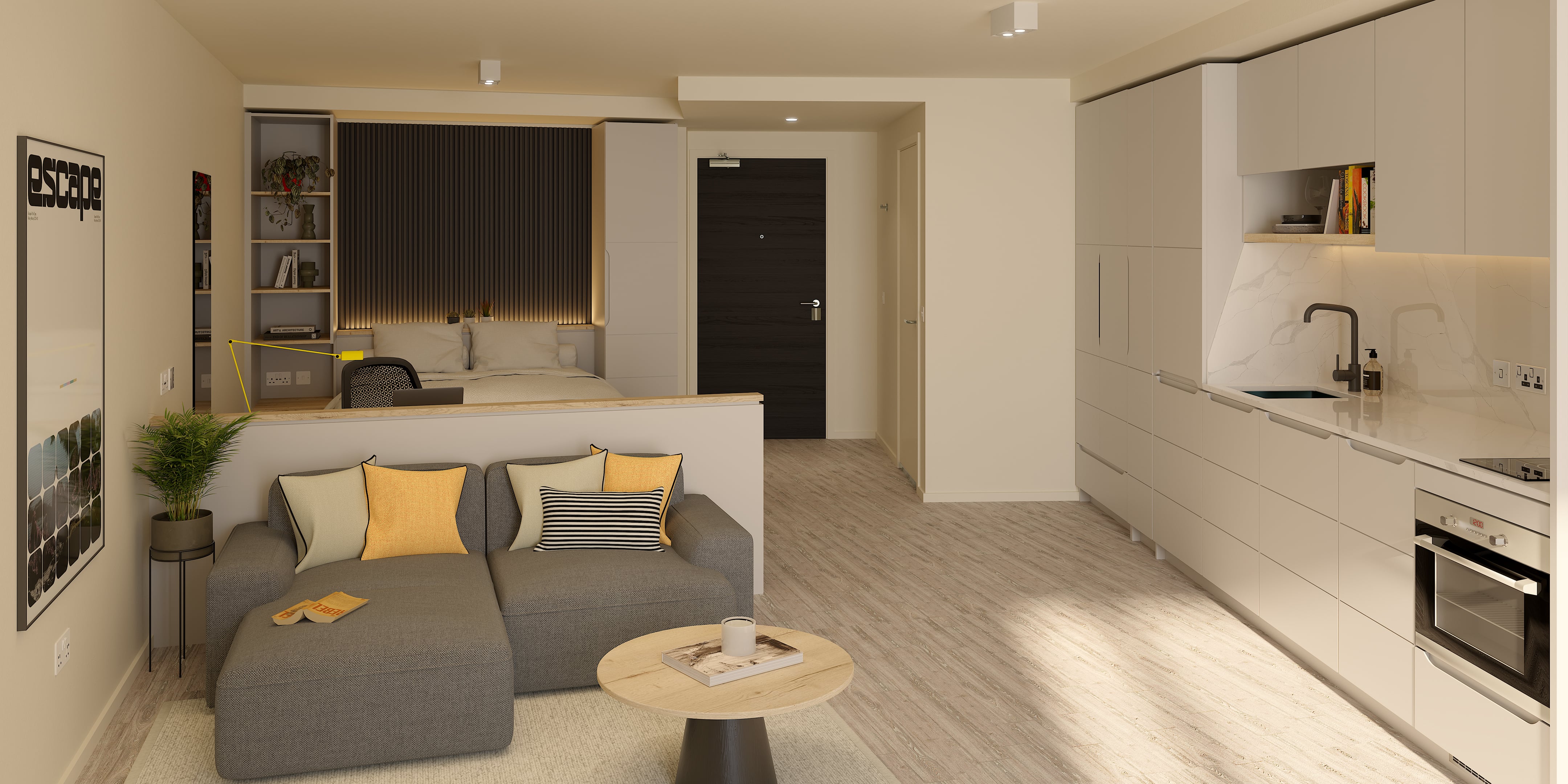 Studio apartment layout with a grey sofa, circular coffee table, and bed area separated by a partial wall, adjacent to a modern kitchen with white cabinets and a dark wood door.